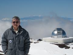 Alan Tokunaga on Mauna Kea with the dome of the NASA IRTF in the background (Photo by Roy Tokunaga).