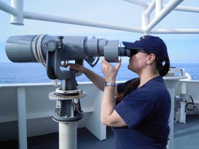 <p>Fig. 1.&nbsp;A biologist on a National Oceanic and Atmosphere Association (NOAA) ship surveys for dolphins and marine turtles to avoid entangling them in research nets.</p>